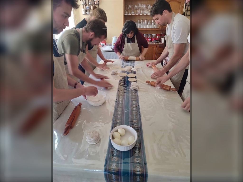 Alumnos estirando la masa con usleros tradicionales junto a Doña Marlene en el taller de cocina